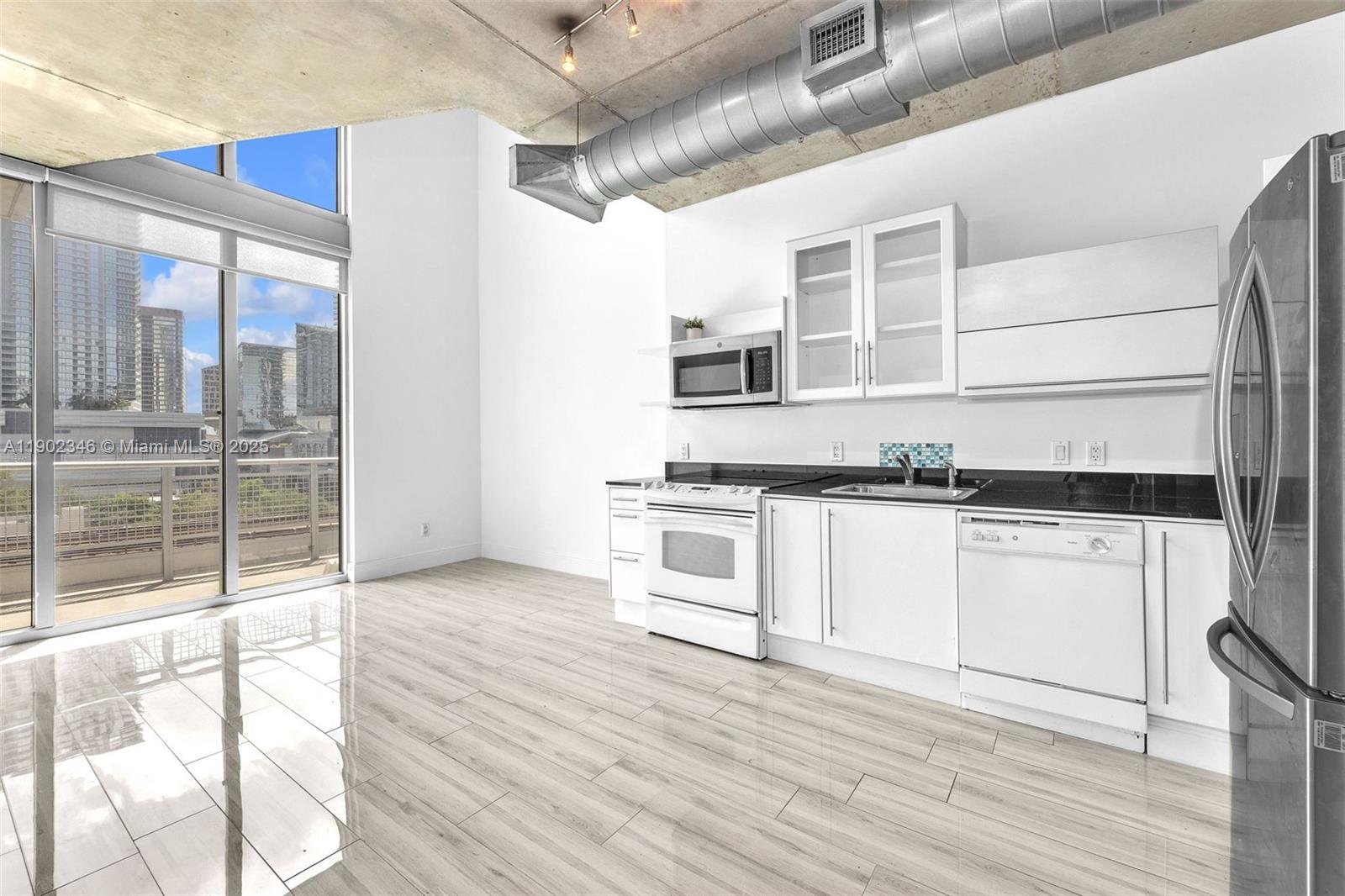 690 Southwest 1st Court, Unit 1008 Miami, FL 33130 - Photo 7 of 20 a kitchen with granite countertop a stove a sink and a refrigerator