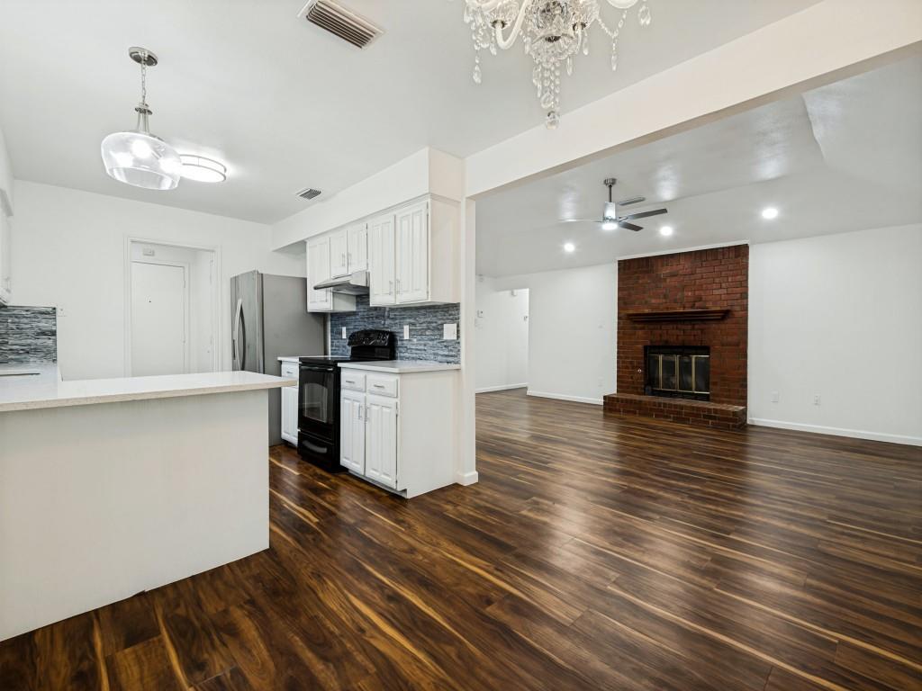 3716 Royal Valley Road Grand Prairie, TX 75052 - Photo 15 of 25 Wood-finish flooring throughout, white cabinetry, integrated stainless steel appliances, brick fireplace, and recessed lighting