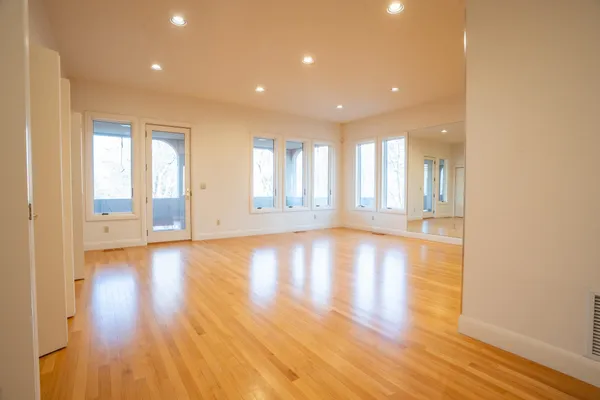 a view of an empty room with wooden floor and a window