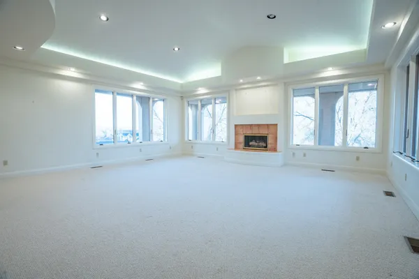 an empty room with windows and fireplace