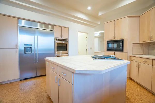 a kitchen with kitchen island a counter top space cabinets and stainless steel appliances