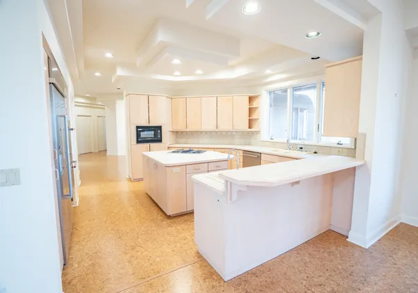 a large white kitchen with kitchen island a sink a stove a refrigerator and white cabinets