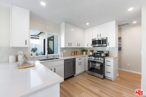 a kitchen with white cabinets stainless steel appliances and sink