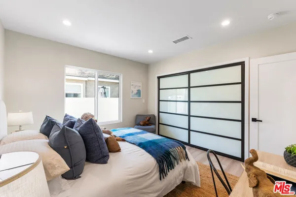 a bedroom with a bed and a dresser next to a window