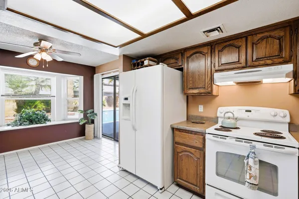 a kitchen with stainless steel appliances granite countertop a refrigerator a stove and a sink with large windows
