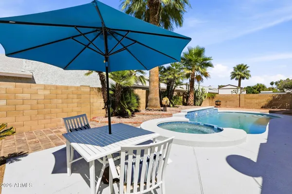 a patio with a table and chairs under an umbrella