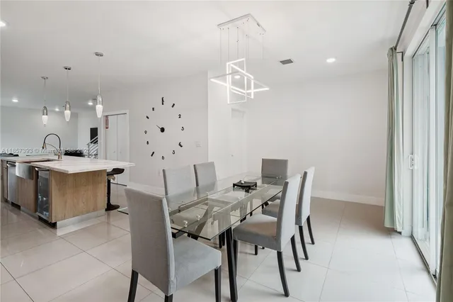 a workspace with stainless steel appliances kitchen island granite countertop a table chairs and a refrigerator