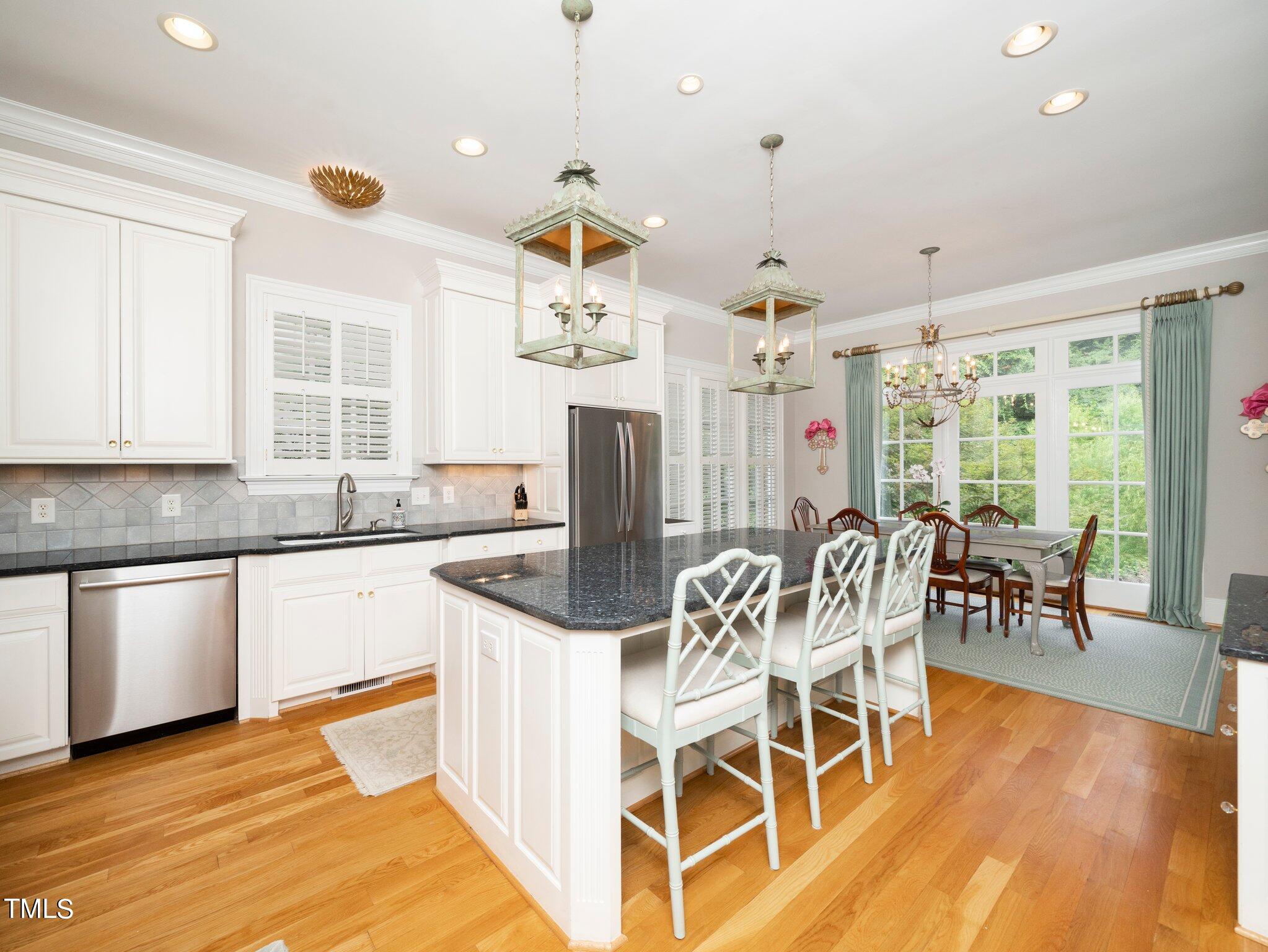 2512 Lewiswood Lane Raleigh, NC 27608 - Photo 8 of 41 a kitchen with stainless steel appliances granite countertop a stove top oven a sink dishwasher a dining table and chairs with wooden floor