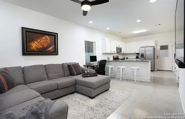 a living room with stainless steel appliances furniture and a view of kitchen