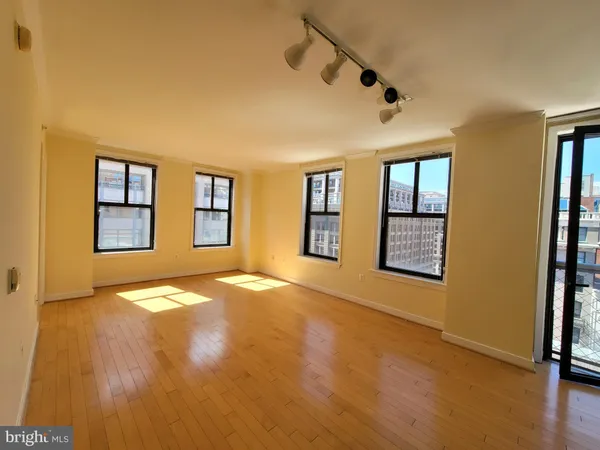a view of an empty room with window and wooden floor