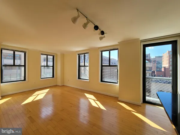 a view of an empty room with window and wooden floor