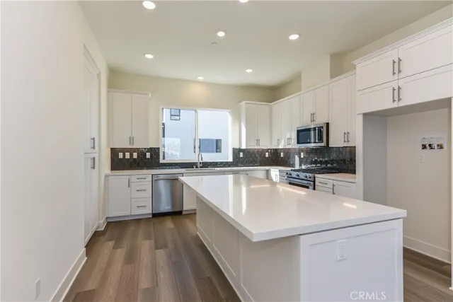 a kitchen with stainless steel appliances a refrigerator sink and white cabinets