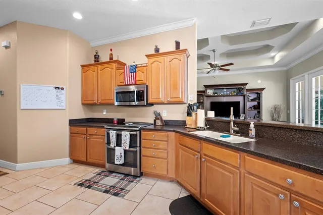 a kitchen with stainless steel appliances kitchen island granite countertop a table chairs stove and white cabinets