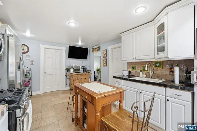 a kitchen with stainless steel appliances granite countertop a stove top oven a sink a refrigerator and white cabinets