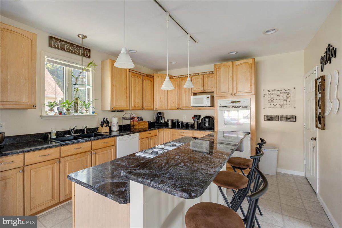 1727 6th Street Ewing, NJ 08638 - Photo 23 of 40 a kitchen with stainless steel appliances granite countertop a stove top oven a sink a dining table and chairs with white cabinets