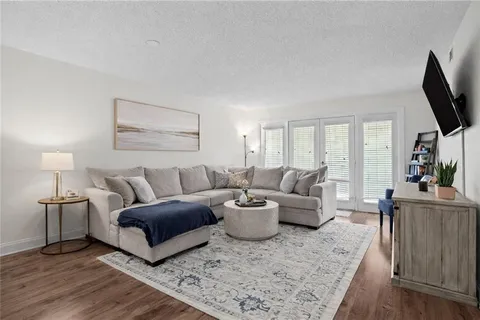 a living room with furniture a flat screen tv and a wooden floor