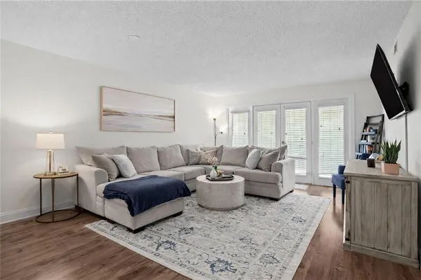 a living room with furniture a flat screen tv and a wooden floor