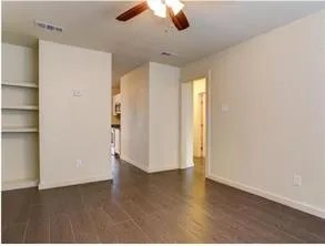 an empty room with wooden floor closet and windows