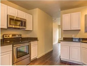 a kitchen with granite countertop a stove top oven microwave and cabinets