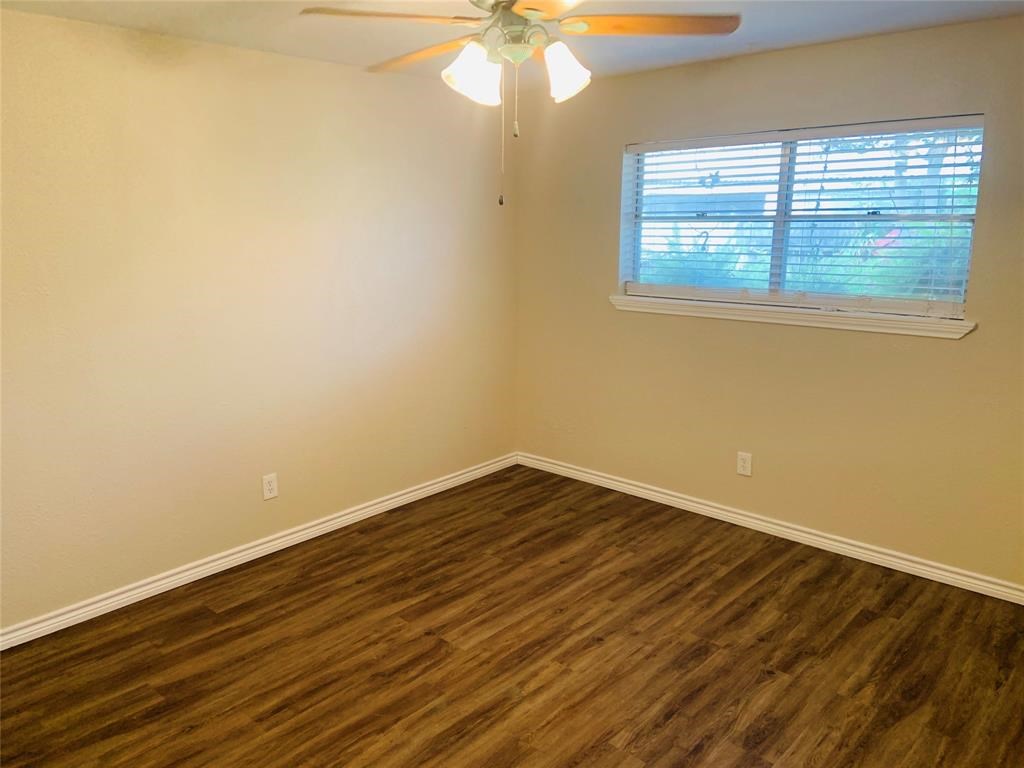 3302 Burke Road, Unit 9 Pasadena, TX 77504 - Photo 12 of 20 a view of an empty room with wooden floor and a window