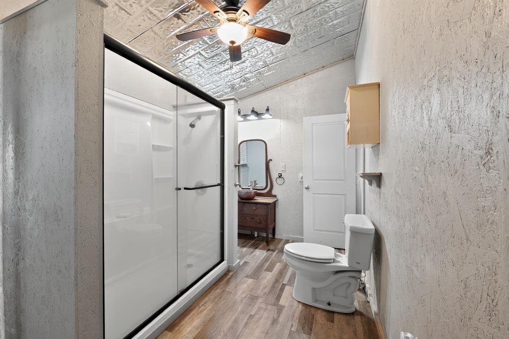 5485 Highway 7 Marlin, TX 76661 - Photo 14 of 36 Full bathroom with a shower stall, lofted ceiling, light wood-type flooring, a textured wall, and a ceiling fan