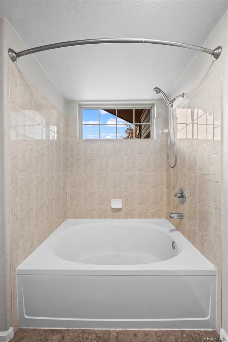 10787 Twenty Mile Road, Unit 301 Parker, CO 80134 - Photo 16 of 31 a bathroom with a bathtub and a shower