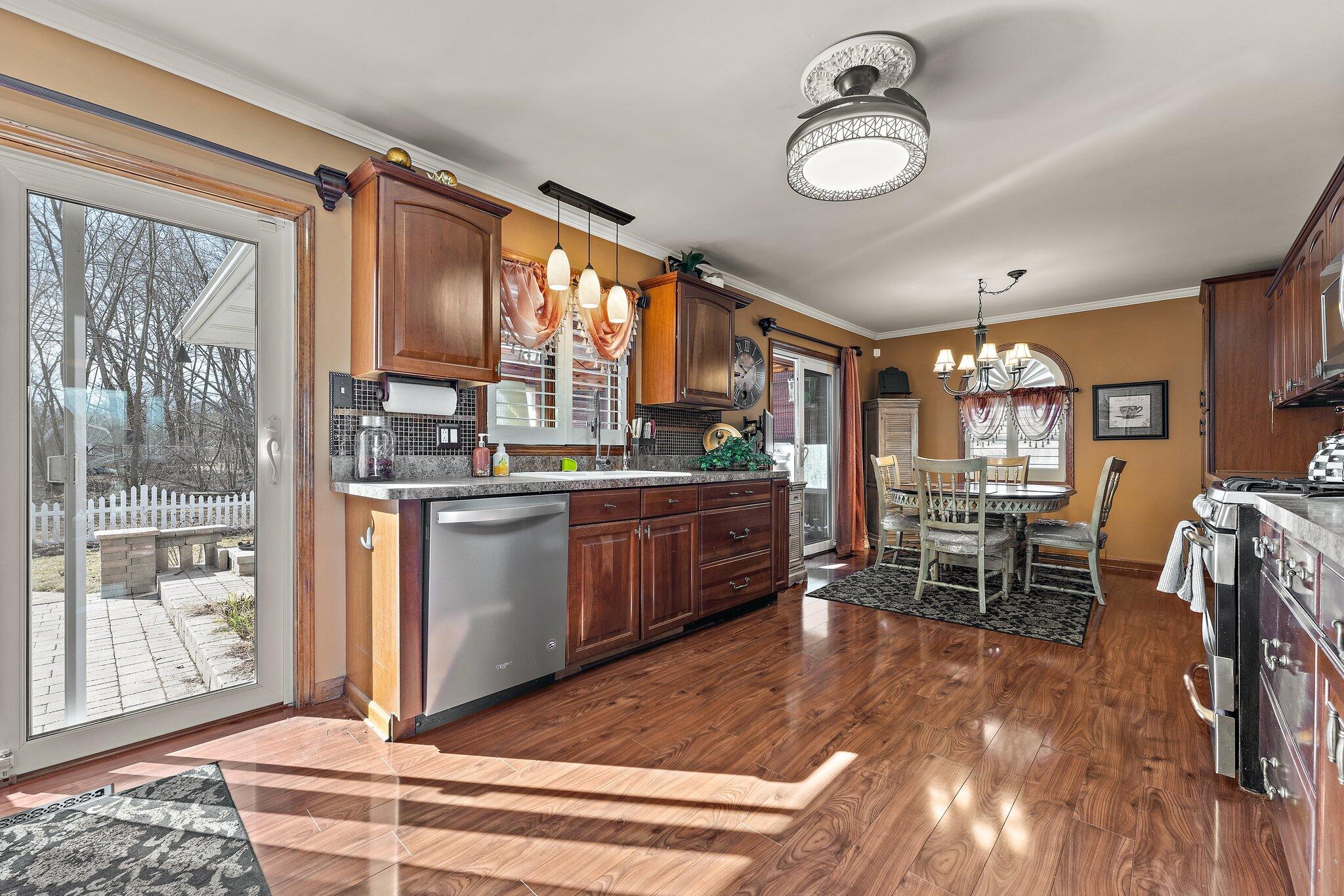 6881 West 86th Court Crown Point, IN 46307 - Photo 7 of 28 a kitchen with stainless steel appliances granite countertop sink stove and wooden cabinets