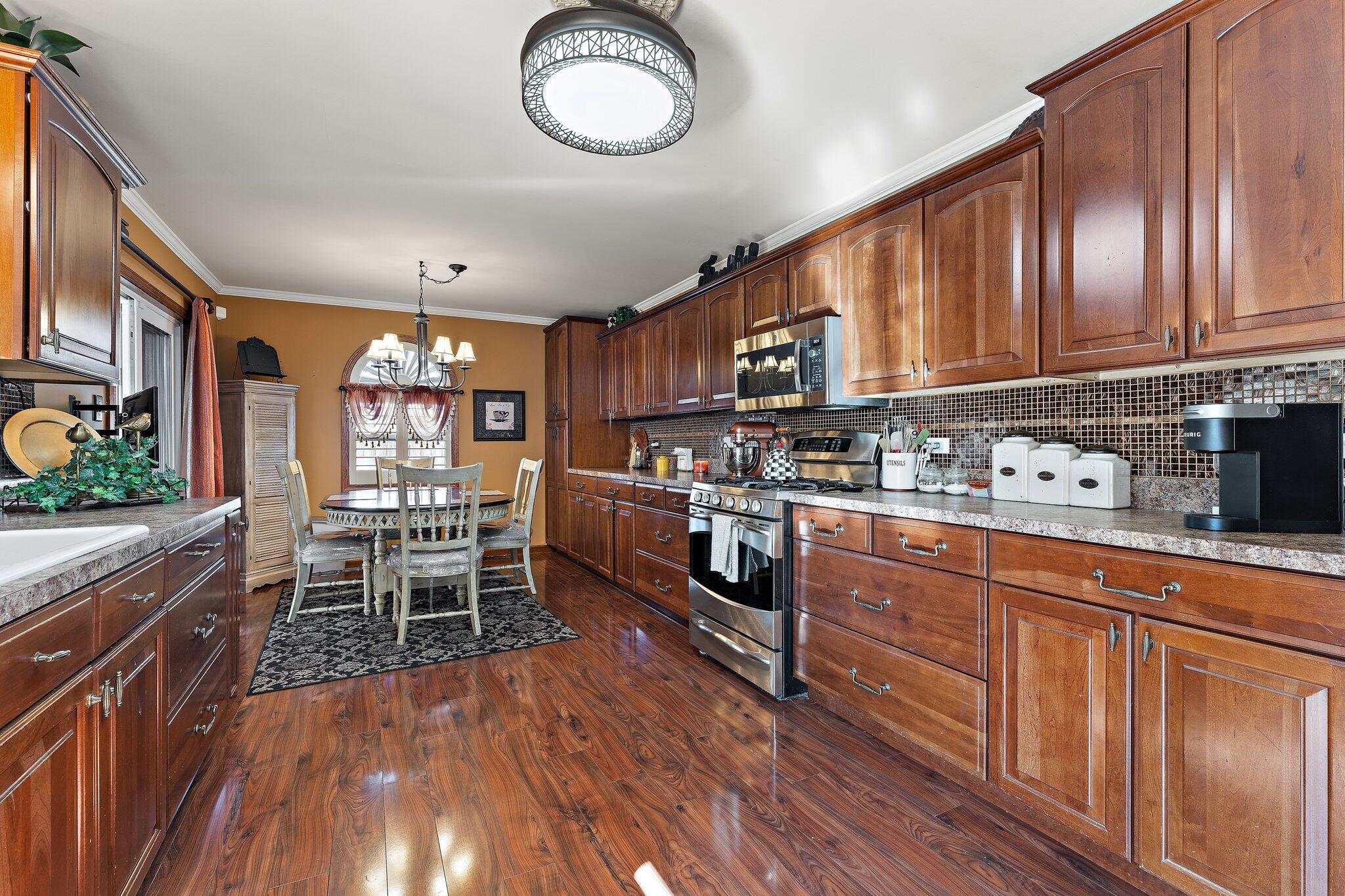 6881 West 86th Court Crown Point, IN 46307 - Photo 8 of 28 a kitchen with stainless steel appliances granite countertop a stove top oven a sink dishwasher and cabinets with wooden floor