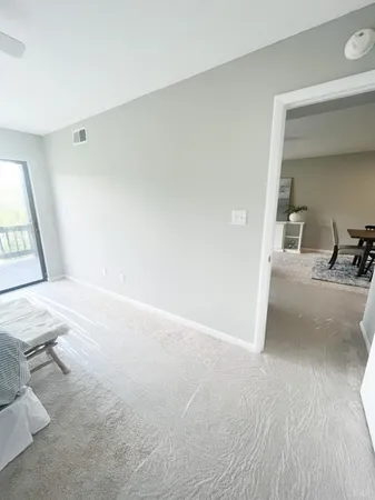 a view of a hallway to a livingroom with wooden floor and furniture