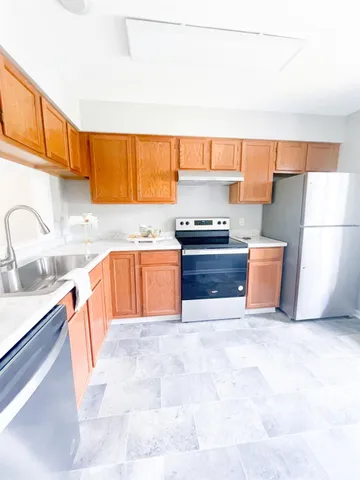 a kitchen with stainless steel appliances a sink a stove a refrigerator cabinets and a window