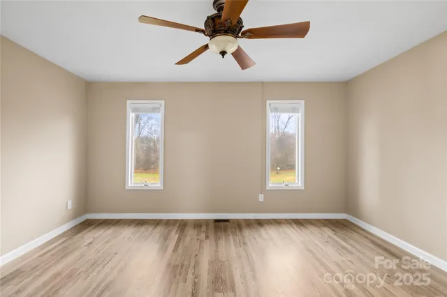 a view of an empty room with window and wooden floor