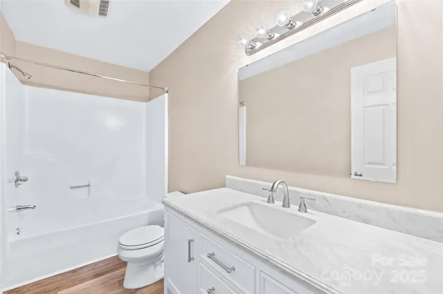 a bathroom with a granite countertop sink a toilet and shower