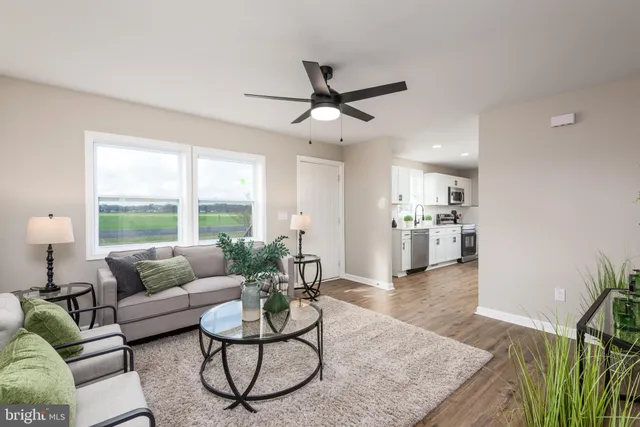 a living room with furniture and a large window with kitchen view