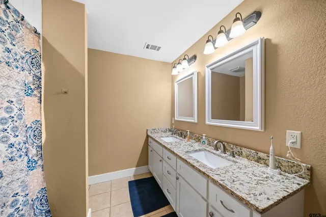 a bathroom with a granite countertop sink vanity and mirror