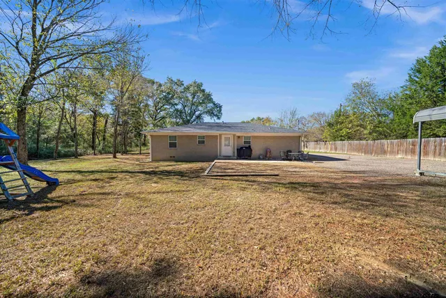a view of a house with backyard and trees