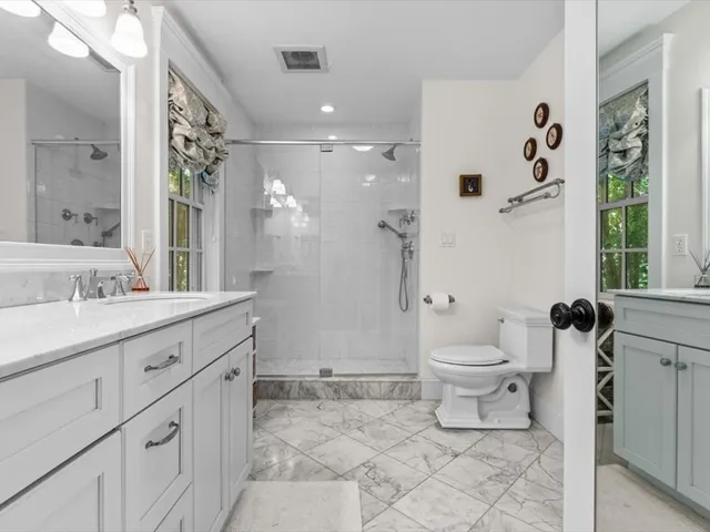 a bathroom with a granite countertop sink toilet a large mirror a shower and a bathtub