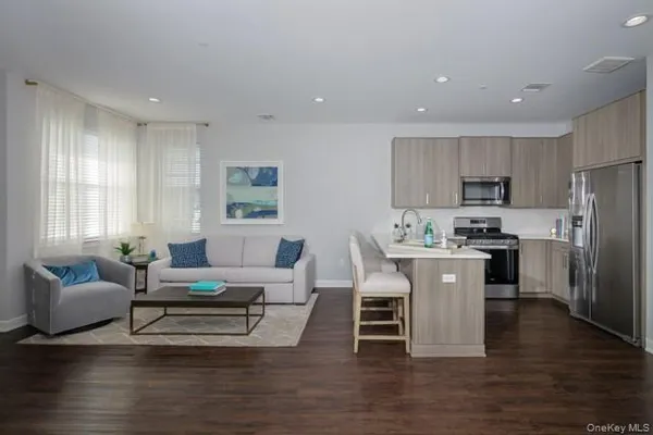 a living room with stainless steel appliances furniture and a wooden floor