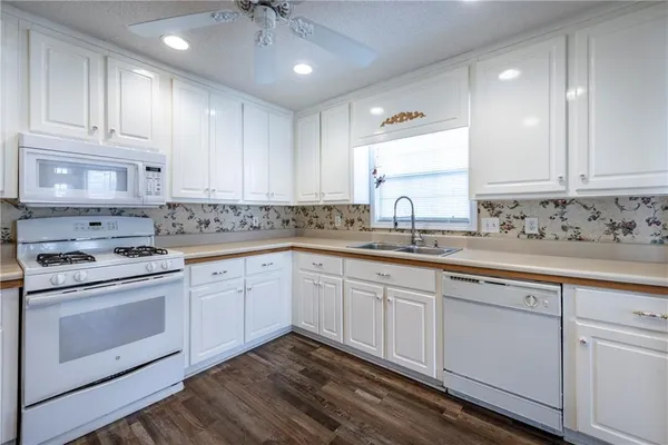 a kitchen with granite countertop white cabinets and white stainless steel appliances