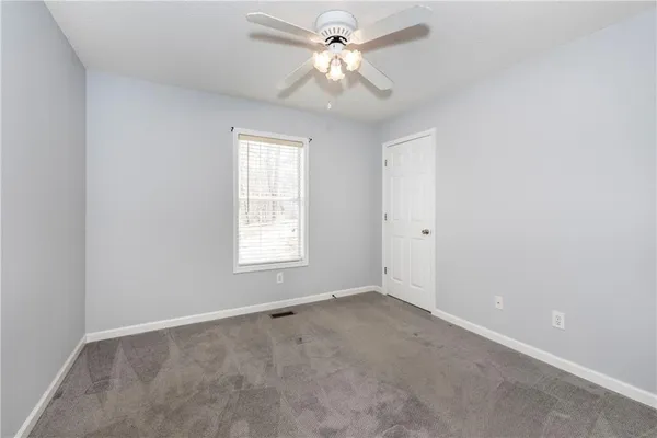 an empty room with a window and a fan