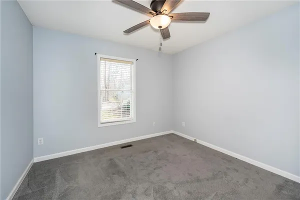 an empty room with a window and a fan