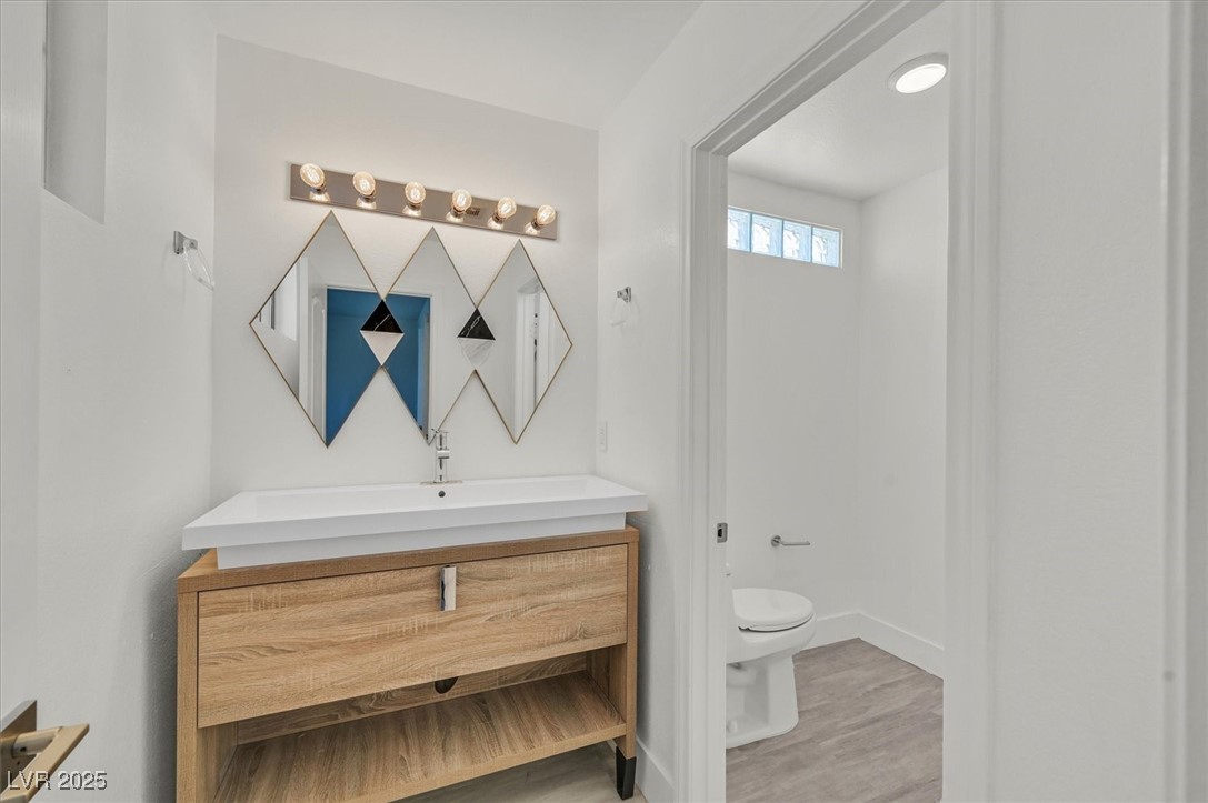 5421 Painted Mirage Road Las Vegas, NV 89149 - Photo 14 of 35 Bathroom featuring wood finished floors, vanity, toilet, and baseboards