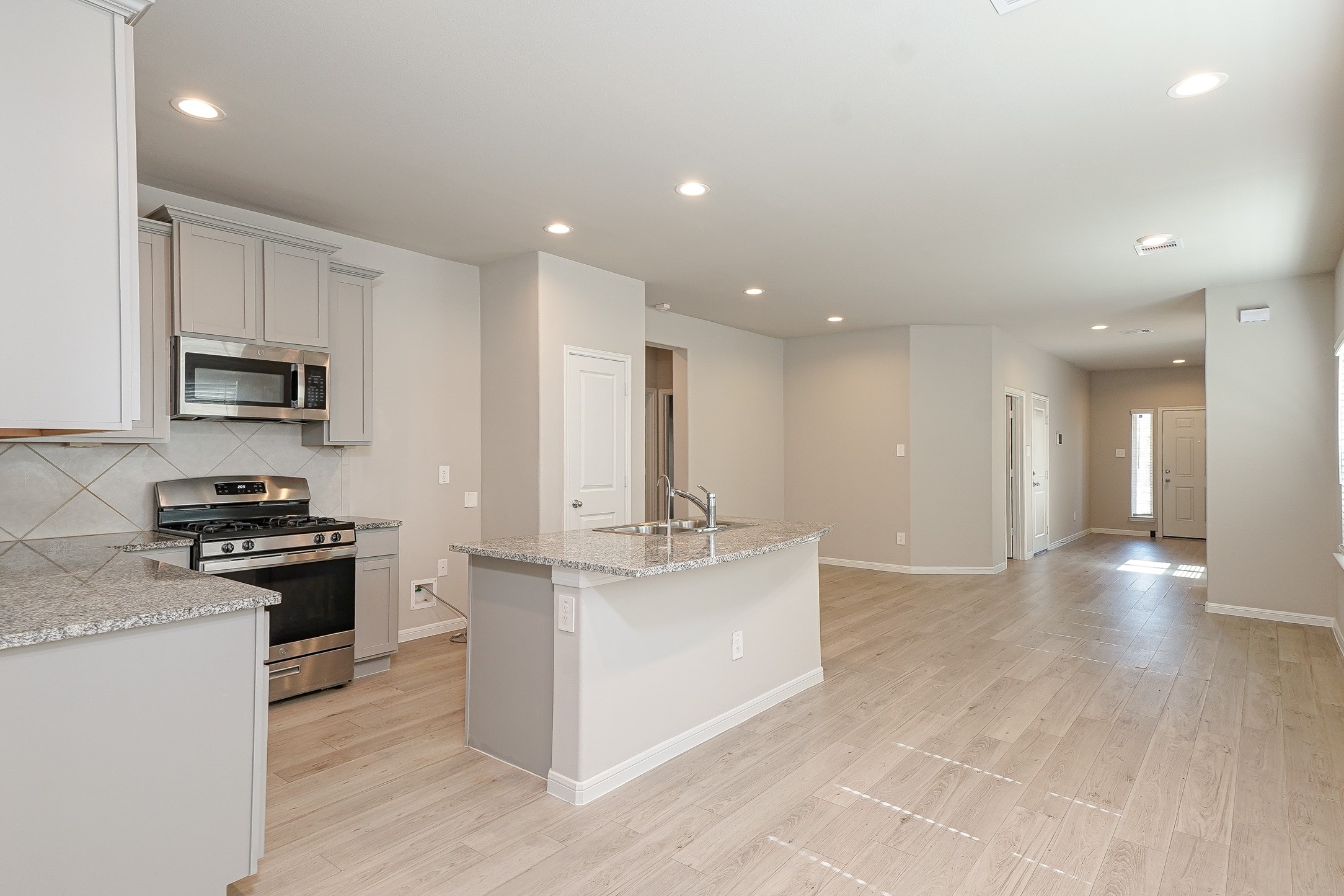 9254 Sea Gdn Street Houston, TX 77034 - Photo 8 of 33 a kitchen with stainless steel appliances granite countertop a stove top oven a sink a refrigerator and white cabinets with wooden floor