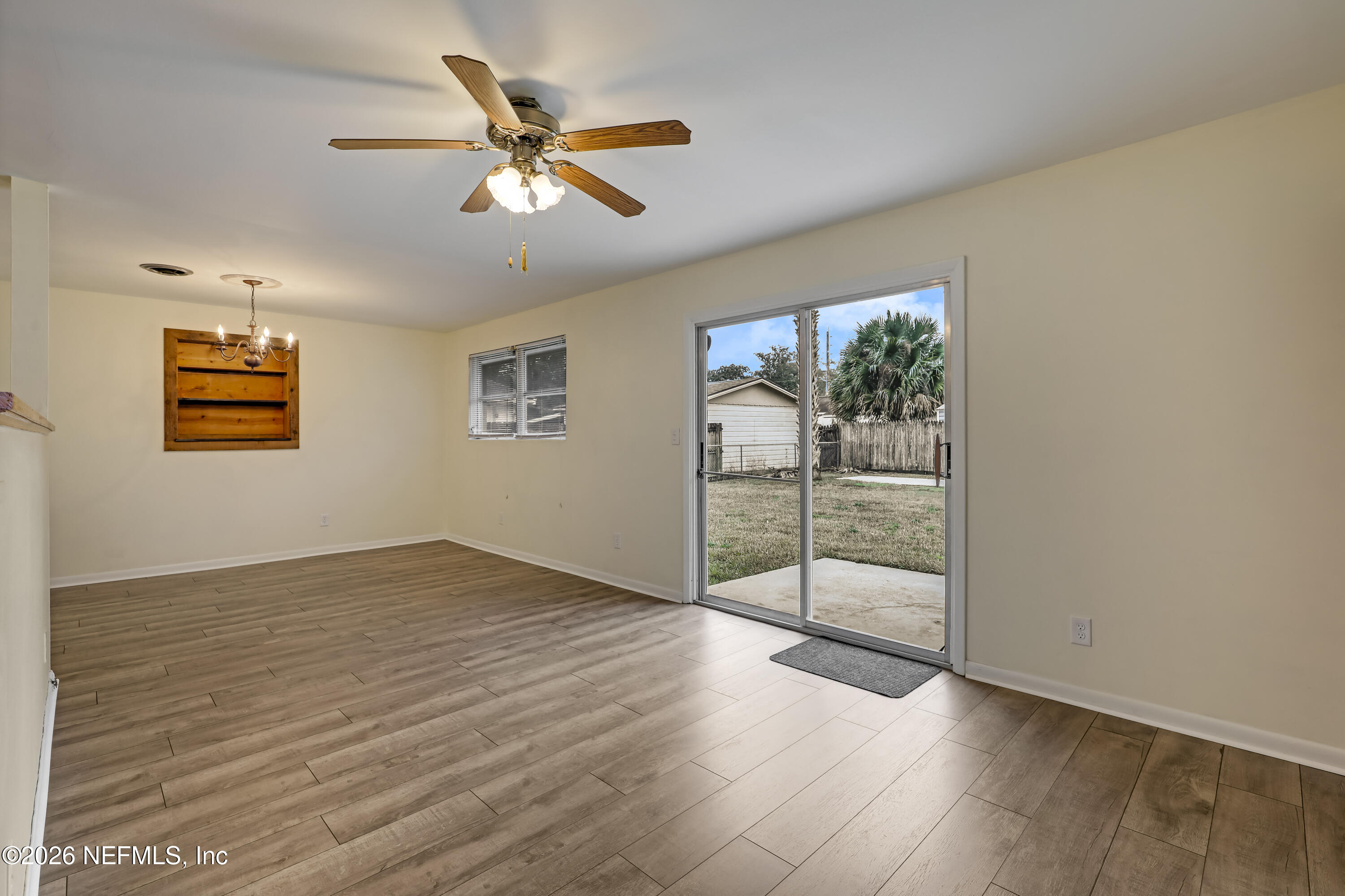 3944 Rodby Drive Jacksonville, FL 32210 - Photo 3 of 40 an empty room with wooden floor fan and windows