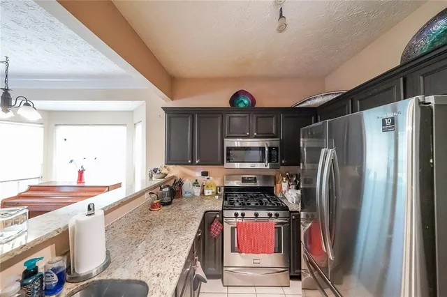 a kitchen with stainless steel appliances granite countertop a refrigerator stove and sink