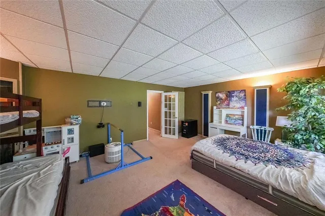 a bedroom with a bed and large trees with outer view