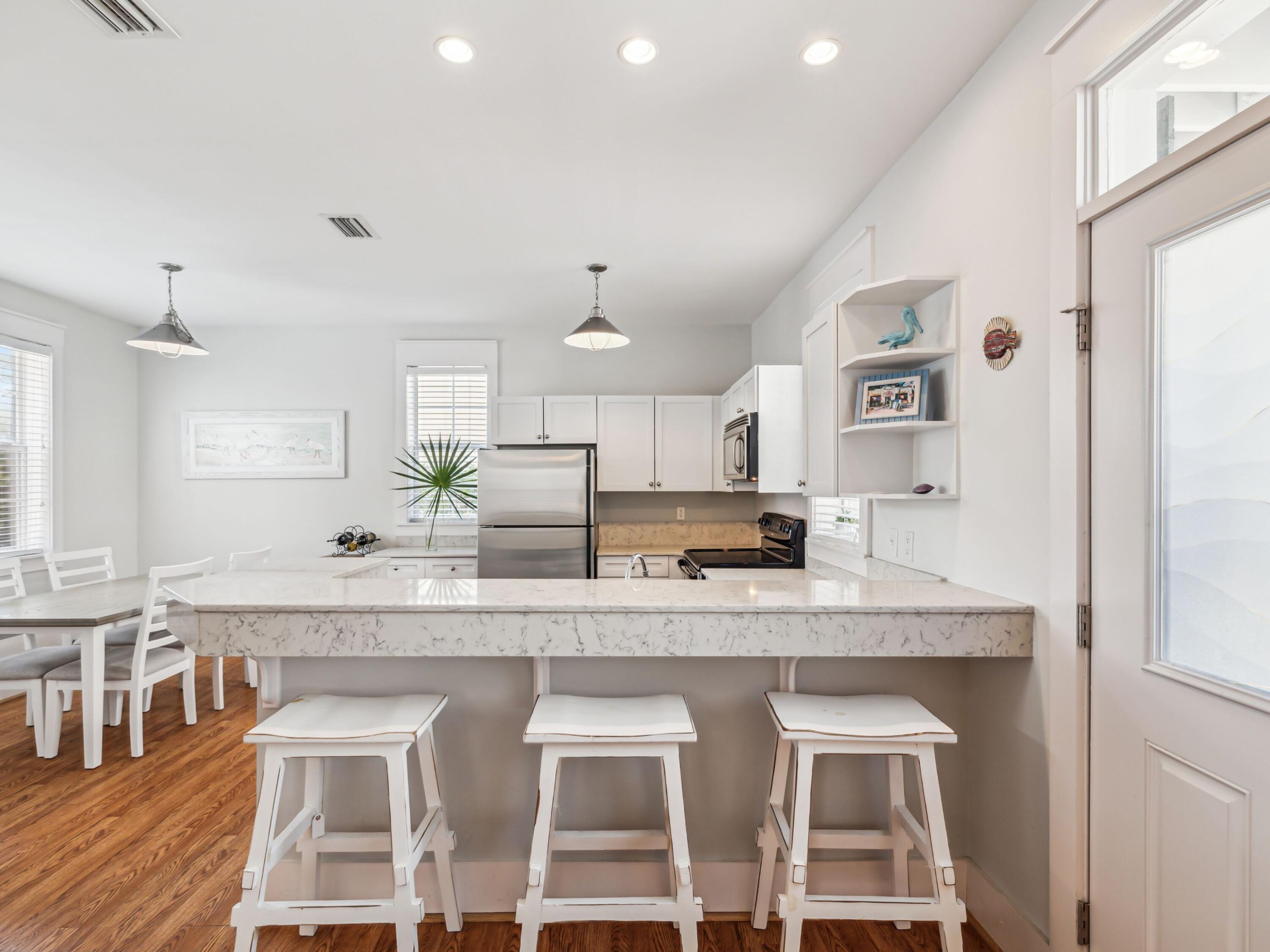 198 Somerset Bridge Road, Unit 103 Santa Rosa Beach, FL 32459 - Photo 4 of 39 a large white kitchen with granite countertop a stove a sink a dining table and chairs
