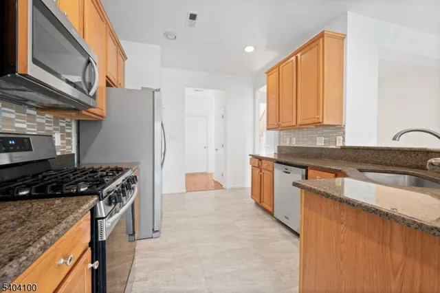 a kitchen with stainless steel appliances granite countertop a sink a stove and a refrigerator