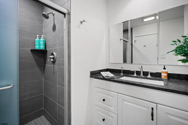 a bathroom with a granite countertop sink a mirror and shower