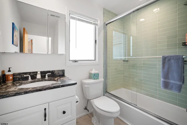 a bathroom with a granite countertop sink a toilet a mirror and shower
