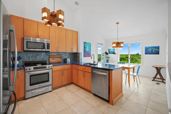 a kitchen with stainless steel appliances a stove center island a stove and a view of living room